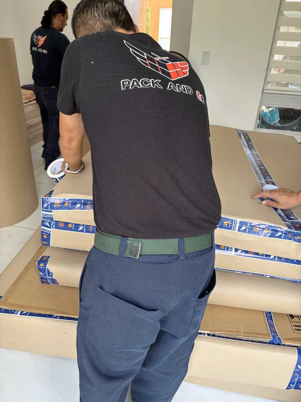 Equipo de Pack And Go ajustando protección de cartón y cinta sobre un mueble